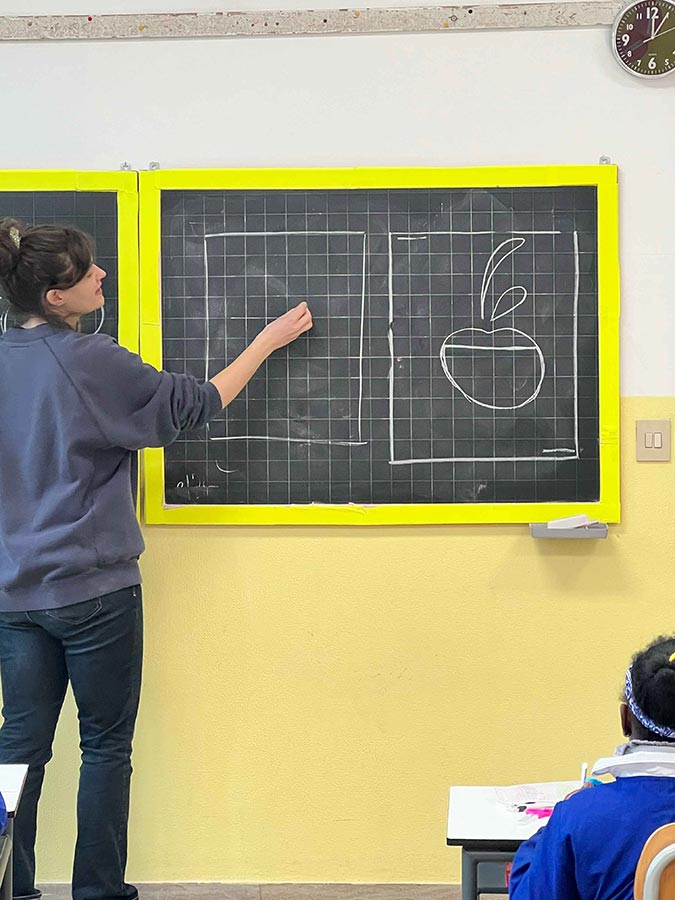 Insegnante alla lavagna che spiega alla classe come disegnare una ciliegia